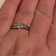 a woman's hand holding a wedding ring with two diamonds on it and the other side