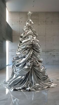 a silver christmas tree is in the middle of an empty room with concrete walls and flooring