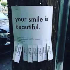 a sign on a telephone pole that says, your smile is beautiful