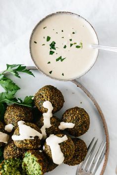 a white plate topped with broccoli covered in ranch dressing next to a fork