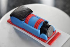 a cake shaped like a train sitting on top of a white plate with red and blue trim