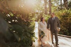 a bride and groom walking down a wooden walkway