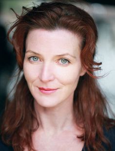 a woman with red hair and blue eyes looking at the camera, wearing a black top