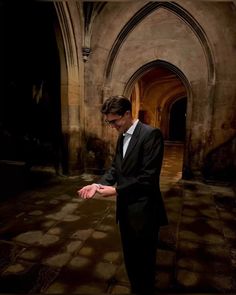 a man in a suit and tie is holding out his hand to touch something on the ground