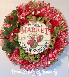 a red and green wreath with strawberries hanging on the wall next to a sign that says farmer's market