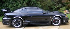 a black sports car parked in front of some trees