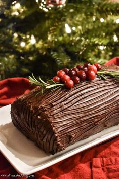 a piece of chocolate cake sitting on top of a white plate next to a christmas tree