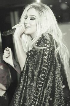 a black and white photo of a woman singing into a microphone