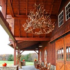 an outdoor covered porch with chairs and deer antlers hanging from the ceiling