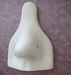 a white ceramic sculpture with a small diamond on it's nose sitting on a purple cloth