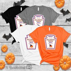 three halloween t - shirts with pumpkins around them on a wooden table and bats in the background