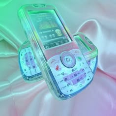 two cell phones sitting next to each other on a pink cloth covered bed sheeted surface