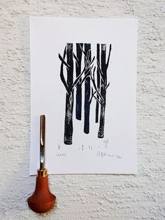 an ink pen is sitting next to a piece of paper with trees drawn on it