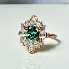 a green and white diamond ring sitting on top of a table