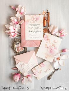 the wedding stationery is laid out on top of each other, with pink flowers