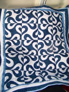 a blue and white quilt on top of a bed next to a pillow with an intricate design