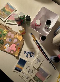 the table is cluttered with craft supplies such as paint, paper and markers on it