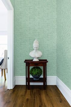 a small table with a vase on it in front of a wallpapered room