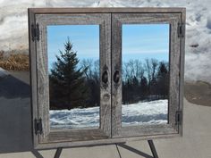 an old wooden cabinet with two mirrors on it's sides in front of snow covered ground