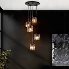 a modern chandelier hanging from the ceiling in a room with black walls and artwork