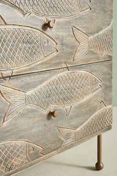 a wooden chest with fish carved on it