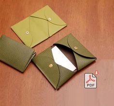 two green envelopes sitting on top of a wooden table next to an empty card case