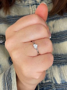 a woman's hand with a diamond ring on her finger, wearing a denim jacket