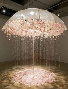 an umbrella with flowers hanging from it in the middle of a floor covered in water