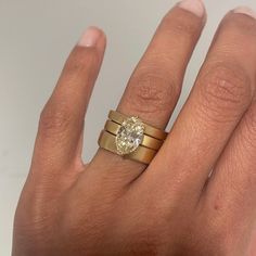 a woman's hand with two gold rings and a diamond ring on top of it