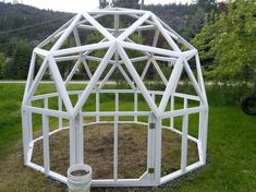 a small white structure sitting on top of a lush green field