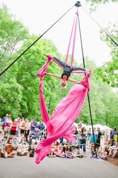 a woman is performing aerial acrobatic tricks in front of a group of people