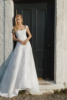 a woman standing in front of a door wearing a wedding dress