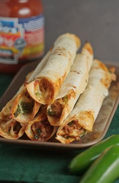 three burritos stacked on top of each other in front of a jar of ketchup