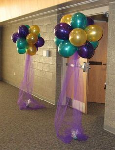 some balloons are hanging from the ceiling in an empty room with purple and green streamers