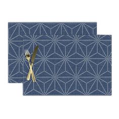 two placemats with gold forks and blue geometric design on the sides, one has a