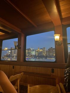 two people sitting at a table looking out over the city from a restaurant with large windows