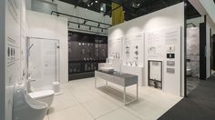 a white bathroom with two sinks and a shower in the middle, surrounded by black and white walls