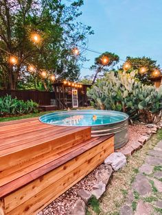 a hot tub in the middle of a wooden deck with lights hanging from it's sides