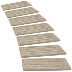 four beige bath mats lined up in the shape of a straight line on a white background