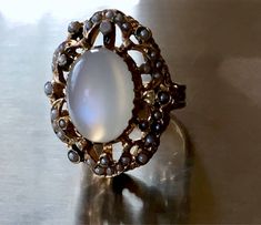 this ring is just incredible!! please see photos! crafted in solid heavy 14k yellow gold and very ornate plus dark enamel and real pearl seeds around!! the rest of enamel is present around the pearls and on the prongs! the pearls are all different in shape and size - because they are natural. all pearl seeds are present, no visible wear to the moonstone! the moonstone is clean and very chatoyant! )with strong chatoyancy effect! - which moves from one side to another as you move your hand!) ! the Vintage Oval Cabochon Moonstone Jewelry, Collectible Oval Cabochon Moonstone Ring, Heirloom Oval Moonstone Ring, Vintage Yellow Gold Oval Moonstone Ring, Antique Moonstone Oval Cabochon Ring, Antique Oval Cabochon Moonstone Ring, Antique Oval Hallmarked Moonstone Ring, Heirloom Moonstone Ring Hallmarked, Vintage Moonstone Gemstone Ring