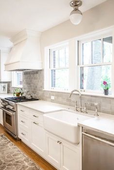 a kitchen with white cabinets, stainless steel appliances and an area rug on the floor