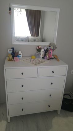 there is a white dresser with drawers and a mirror on it in the corner, next to a window