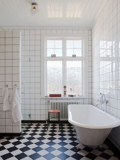 a white bath tub sitting next to a black and white checkered floored bathroom