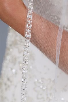 a close up of a bride's arm wearing a veil and beaded dress