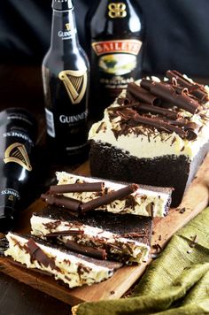 a wooden cutting board topped with cake next to bottles of beer