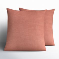 two peach colored pillows sitting next to each other