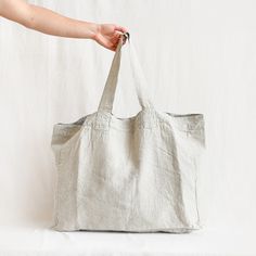 a hand holding a white bag on top of a white surface with the bottom half open