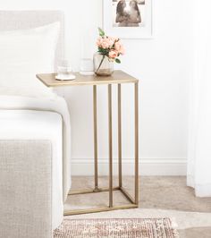 a gold side table with flowers on it and a white couch in the back ground