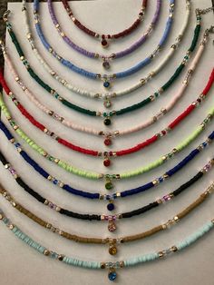 a bunch of necklaces that are sitting on a table next to each other with different colored beads