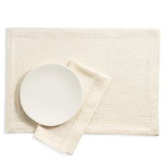 a white plate and napkin sitting on top of a place mat next to each other